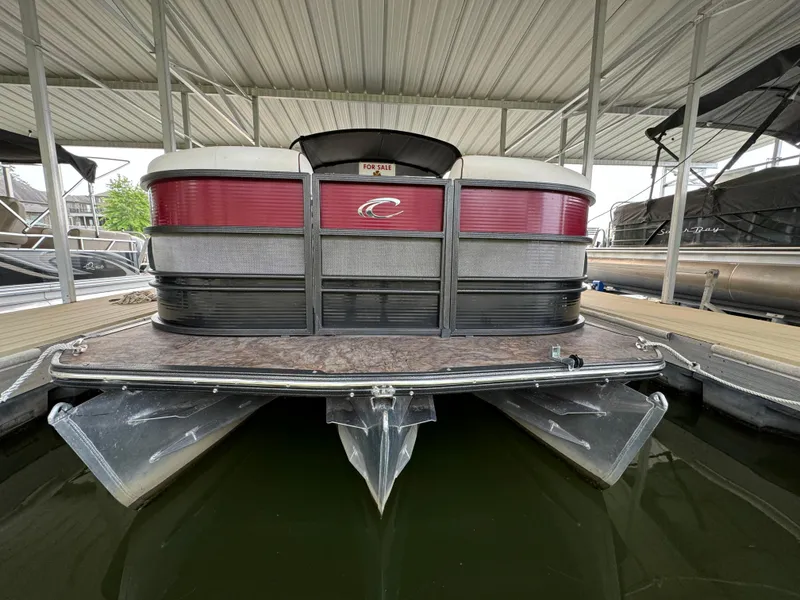 Slide: The Image of 2019 Crest Caribbean 250 SLRC pontoon boat docked under a covered marina. - 2