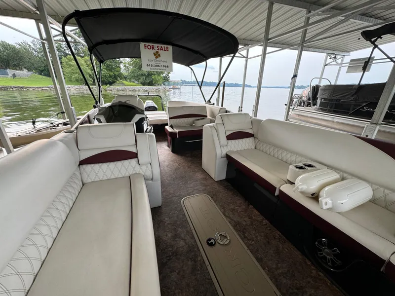 Slide: The Image of 2019 Crest Caribbean 250 SLRC pontoon boat interior with seating, under a covered dock, for sale sign visible. - 9