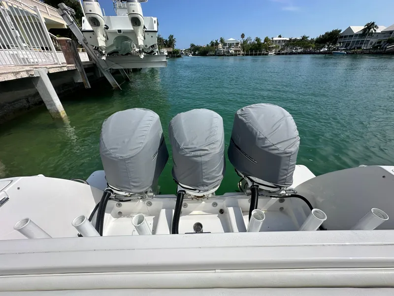 Slide: The Image of 2015 Intrepid 400 Center Console with triple outboard engines, docked in a serene waterfront setting. - 5