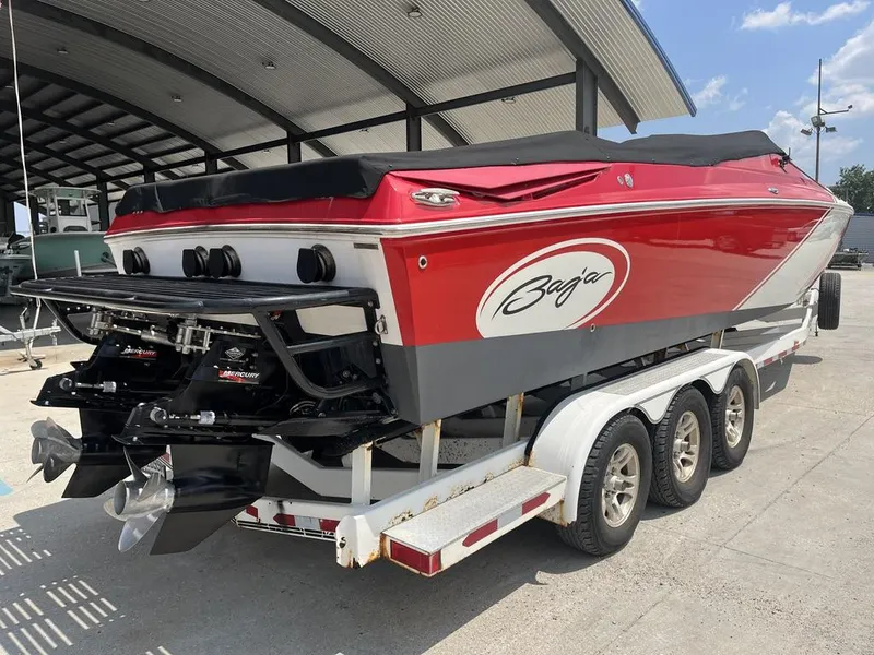 Slide: The Image of 2013 Baja 35 Outlaw speedboat on trailer, red and white design, parked under a canopy. - 12