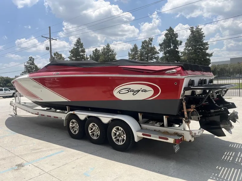 Slide: The Image of 2013 Baja 35 Outlaw speedboat on trailer, red and white design, parked outdoors. - 2