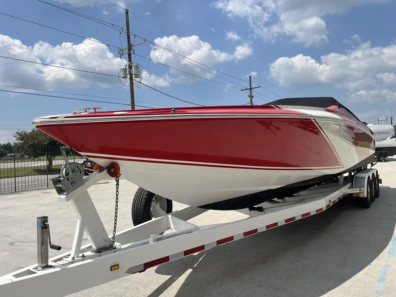 Slide: The Image of 2013 Baja 35 Outlaw speedboat on trailer, red and white design, sunny day. - 5