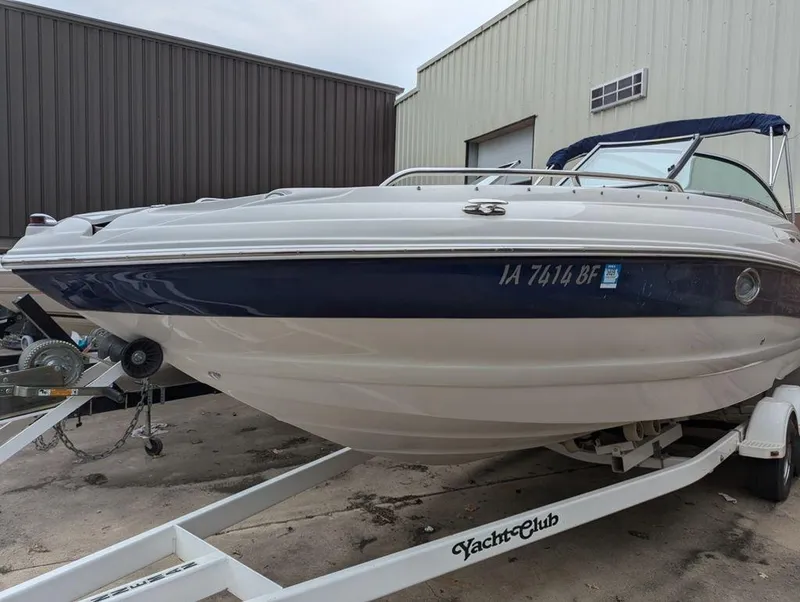 Slide: The Image of 2009 Crownline 240 LS boat on trailer, parked near industrial building. - 0