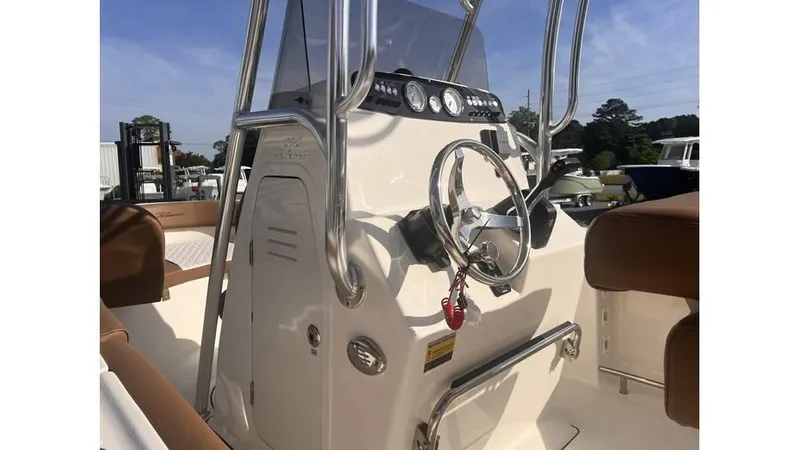 Slide: The Image of 2025 Pioneer 202 Islander boat console with steering wheel and controls, featuring brown seating. - 2