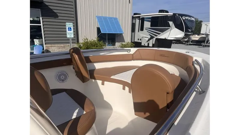 Slide: The Image of 2025 Pioneer 202 Islander boat interior with brown seating, parked near RVs and a building. - 3