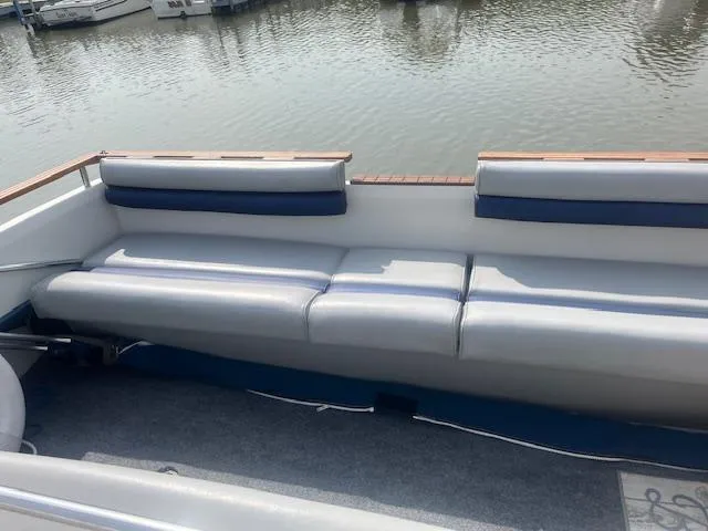 Slide: The Image of 1988 Regal 277 Commodore XL boat interior with cushioned seating by the water. - 13