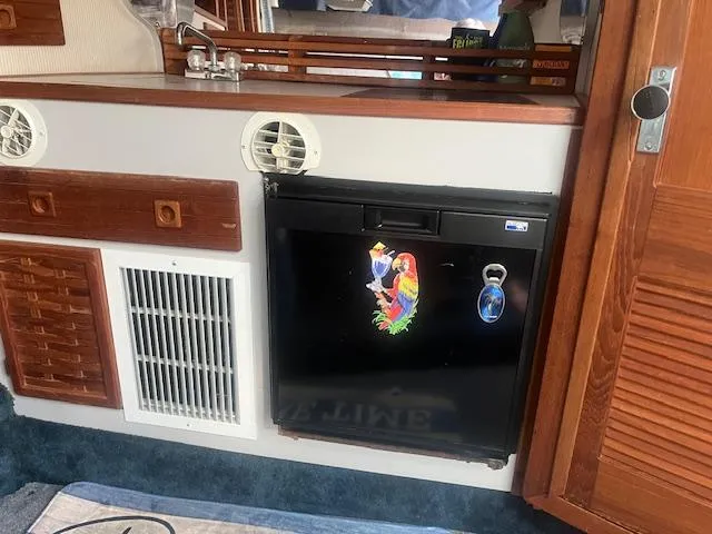 Slide: The Image of 1988 Regal 277 Commodore XL cabin interior with fridge, wooden cabinets, and colorful parrot magnet. - 20