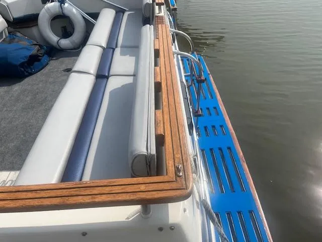Slide: The Image of 1988 Regal 277 Commodore XL boat with wooden railing and blue deck by the water. - 7