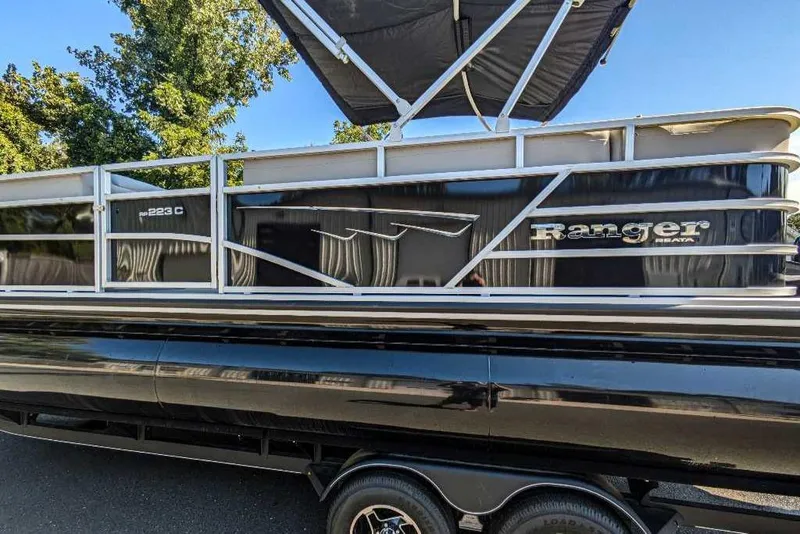 Slide: The Image of 2024 Ranger Reata 223C pontoon boat with sleek black exterior and canopy. - 5