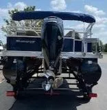 Slide: The Image of 2024 Ranger Reata 200F pontoon boat with outboard motor, parked on a trailer. - 2