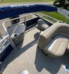 Slide: The Image of 2024 Ranger Reata 200F pontoon boat interior with beige seating and blue canopy. - 7