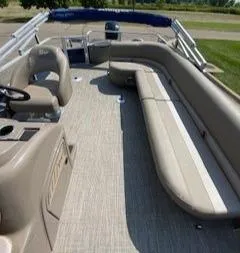 Slide: The Image of 2024 Ranger Reata 200F pontoon boat interior with beige seating and steering console. - 9