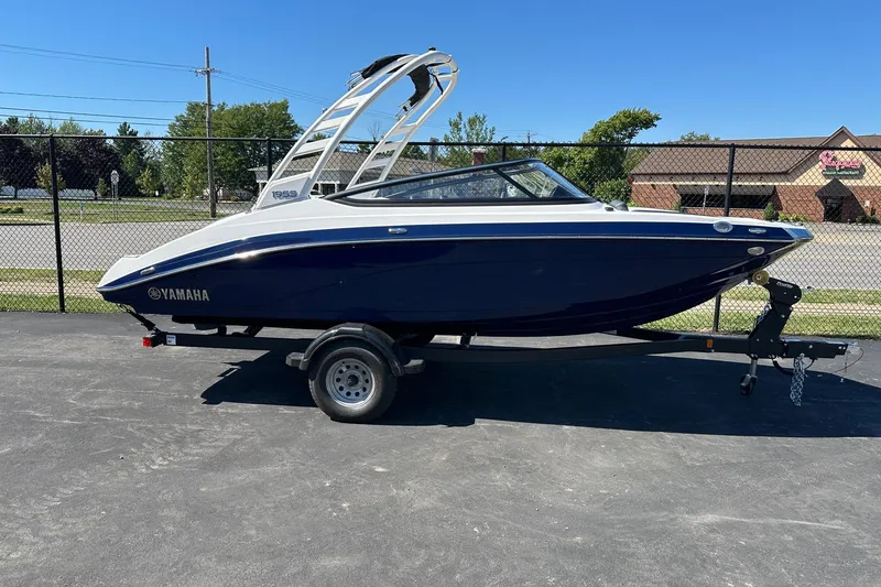The Image of 2026 Yamaha Boats 195S on trailer, sleek design, blue and white color, parked outdoors. - 0