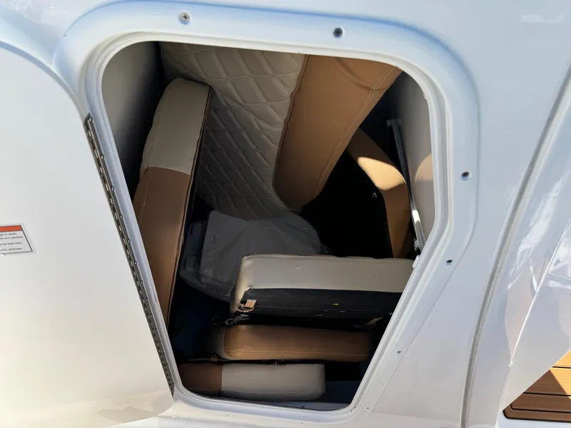 Slide: The Image of 2025 NauticStar 24 OSL boat storage compartment with cushioned seating. - 11