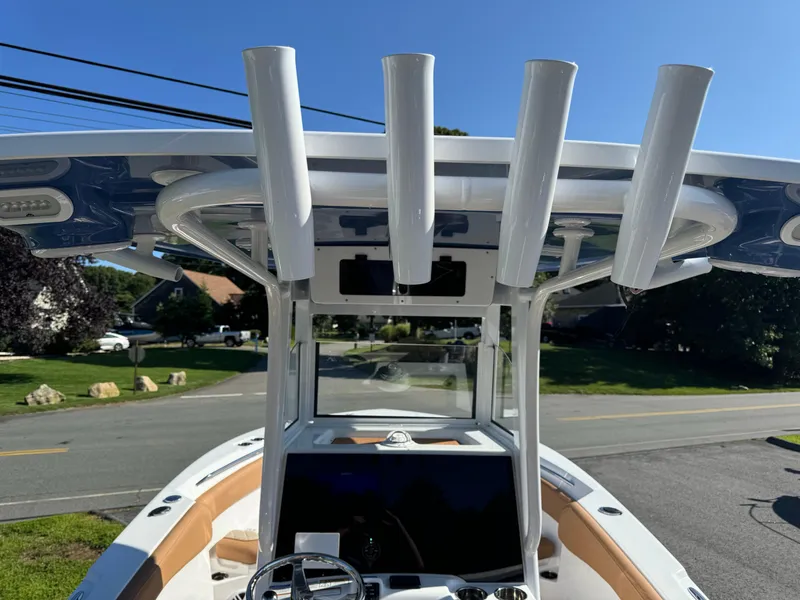 Slide: The Image of 2025 NauticStar 24 OSL boat with T-top and rod holders, parked on a sunny street. - 14