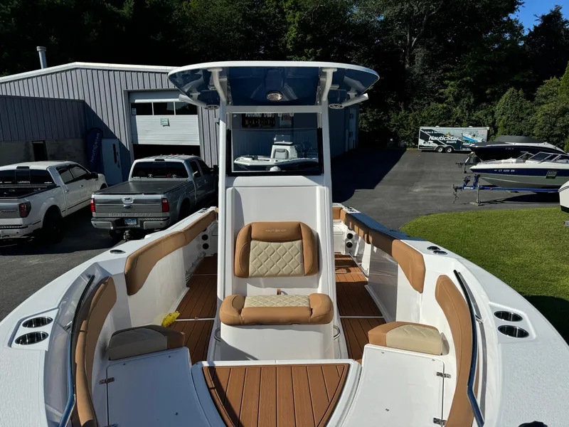 Slide: The Image of 2025 NauticStar 24 OSL boat with tan seating and sleek design in a marina setting. - 6