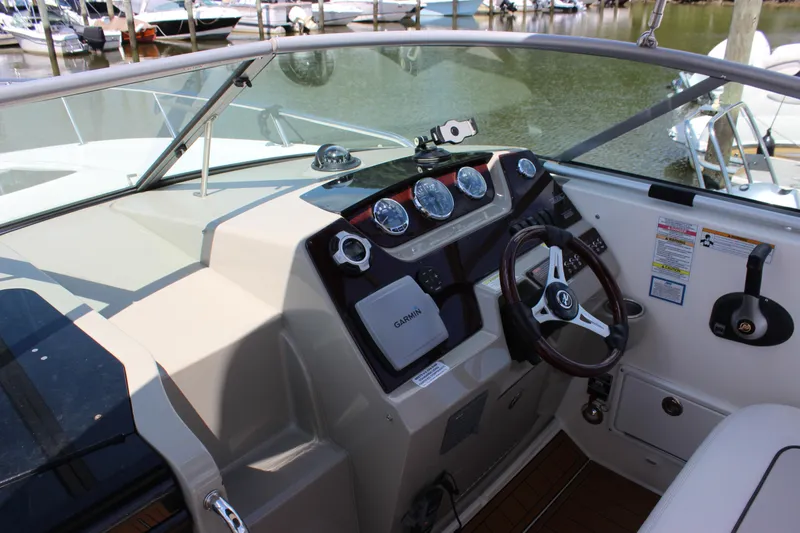 Slide: The Image of 2012 Sea Ray 280 Sundancer helm with steering wheel and gauges, docked at marina. - 12