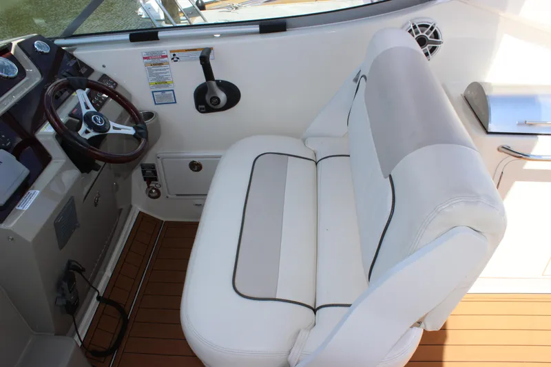 Slide: The Image of 2012 Sea Ray 280 Sundancer helm with white seating and wooden flooring. - 13