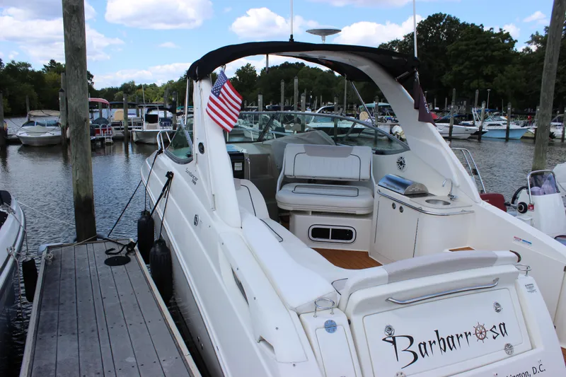 Slide: The Image of 2012 Sea Ray 280 Sundancer docked at marina, featuring American flag and spacious seating. - 45
