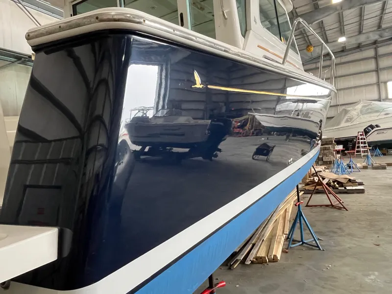 Slide: The Image of 2014 Back Cove 34 Hard Top boat in a storage facility, showcasing sleek blue hull design. - 10