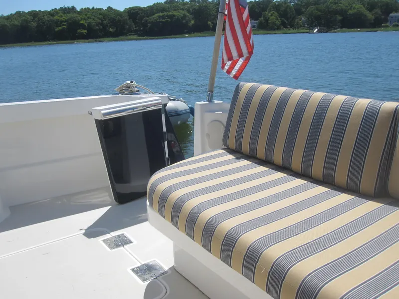 Slide: The Image of Back Cove 34 Hard Top 2014 boat with striped seating and American flag on a sunny day. - 52