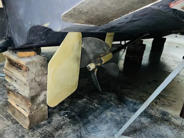 Slide: The Image of 2006 Carolina Classic 28 boat propeller and rudder on wooden blocks. - 13