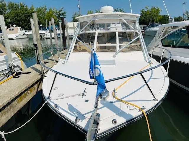 Slide: The Image of 2006 Carolina Classic 28 boat docked at marina, front view with blue flag. - 2