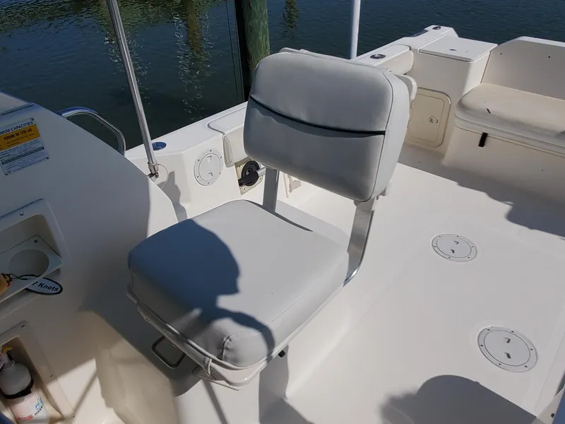 Slide: The Image of 1999 Pursuit 2470 Walkaround boat seat with white upholstery and deck view. - 13