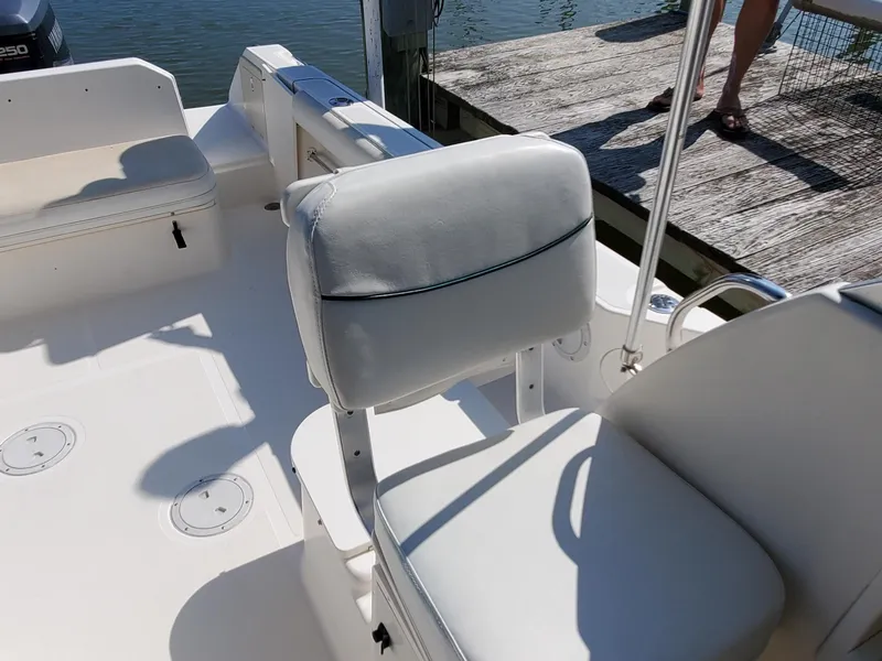 Slide: The Image of 1999 Pursuit 2470 Walkaround boat interior with white seating near dock. - 14