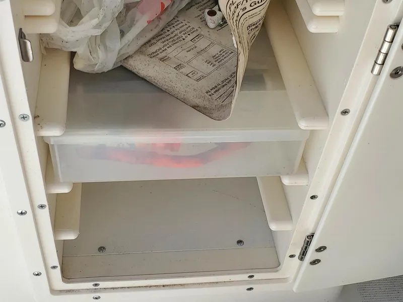 Slide: The Image of Storage compartment in a 1999 Pursuit 2470 Walkaround boat with shelves and items. - 16