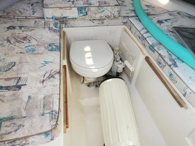 Slide: The Image of 1999 Pursuit 2470 Walkaround cabin interior with toilet and patterned seating. - 19