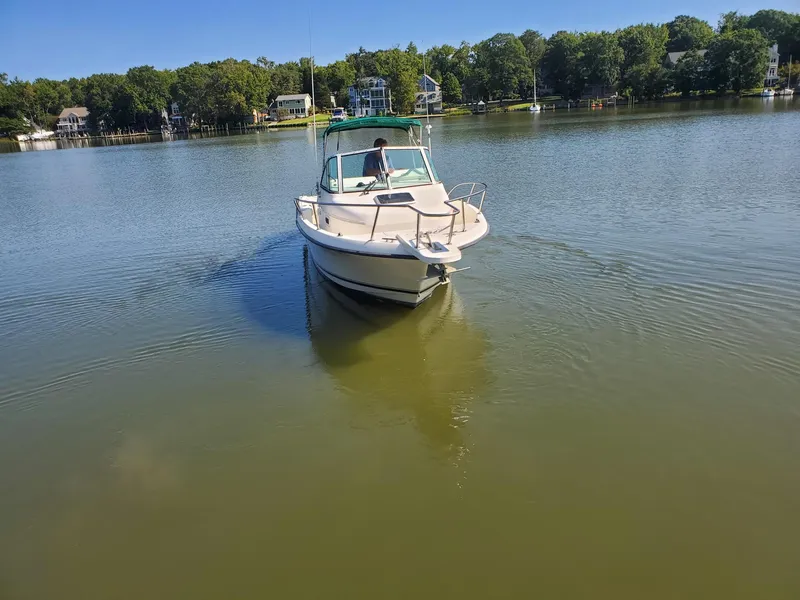 Slide: The Image of 1999 Pursuit 2470 Walkaround boat on calm lake with trees in background. - 4