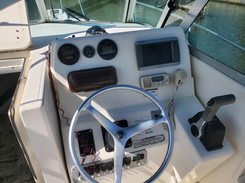 Slide: The Image of 1999 Pursuit 2470 Walkaround boat dashboard with steering wheel and navigation instruments. - 9