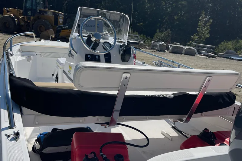 Slide: The Image of 2022 Edgewater 158CS boat interior with steering wheel and seating, parked outdoors. - 10