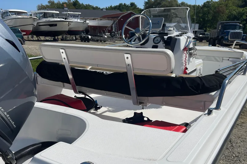 Slide: The Image of 2022 Edgewater 158CS boat interior with steering wheel, seats, and motor, parked among other boats. - 12