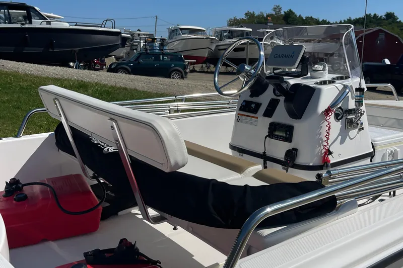 Slide: The Image of 2022 Edgewater 158CS boat interior with steering console and seating, docked outdoors. - 13