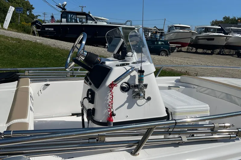 Slide: The Image of 2022 Edgewater 158CS boat console with steering wheel and controls, docked near other boats. - 14