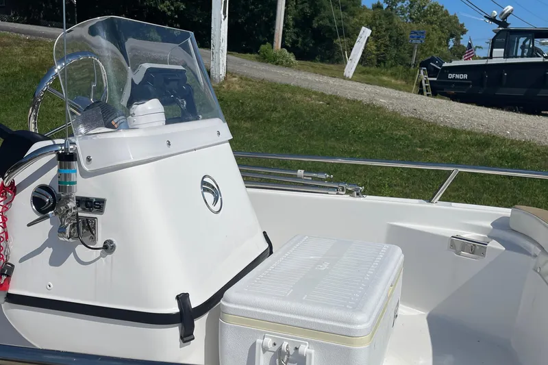 Slide: The Image of 2022 Edgewater 158CS boat interior with console and cooler on a sunny day. - 15