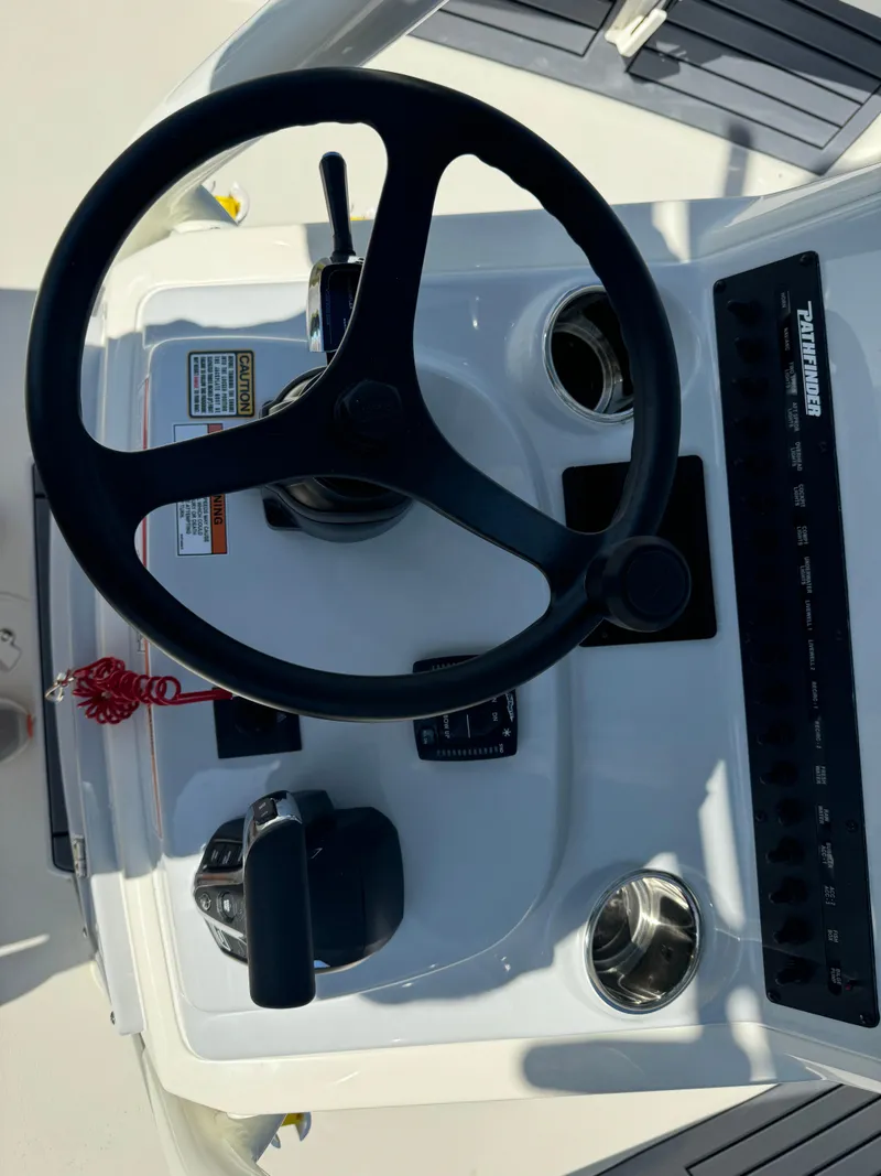 Slide: The Image of Steering console of 2025 Pathfinder 2500 Hybrid boat with controls and cup holders. - 17