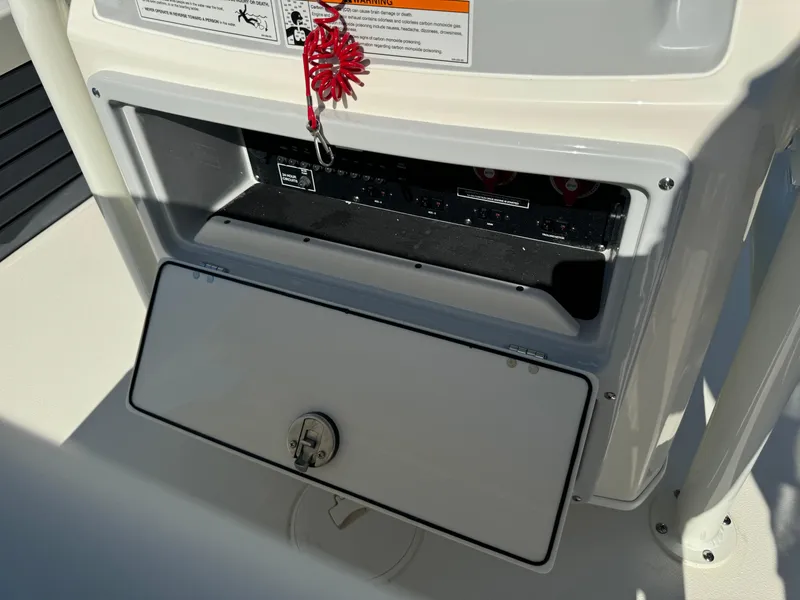Slide: The Image of Pathfinder 2500 Hybrid 2025 boat console with open storage compartment and safety lanyard. - 21