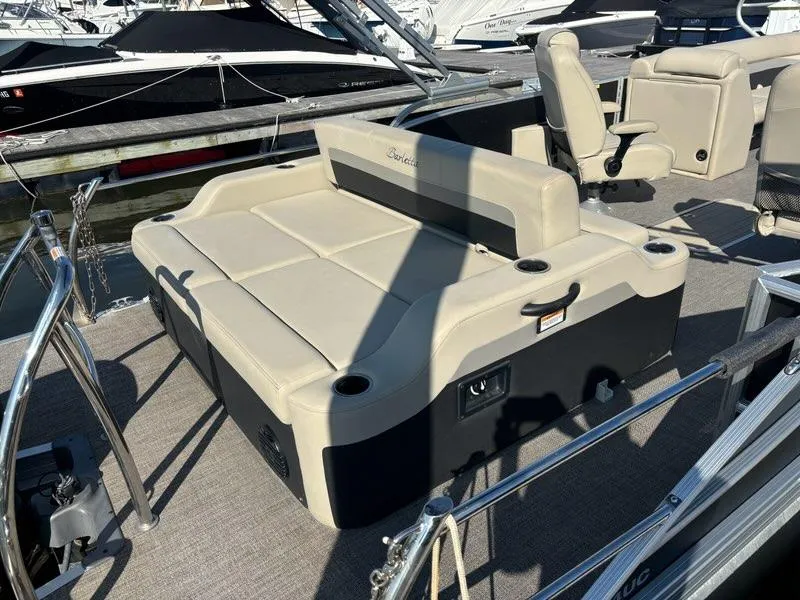 Slide: The Image of 2021 Barletta C24UC pontoon boat with beige seating and cup holders at a marina. - 4