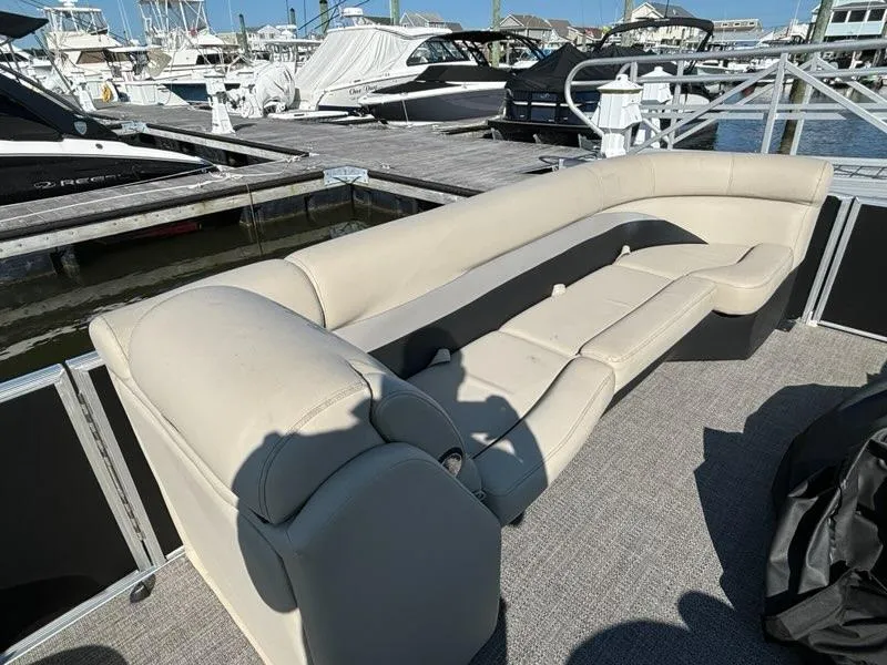 Slide: The Image of 2021 Barletta C24UC pontoon boat with beige seating at a marina. - 8