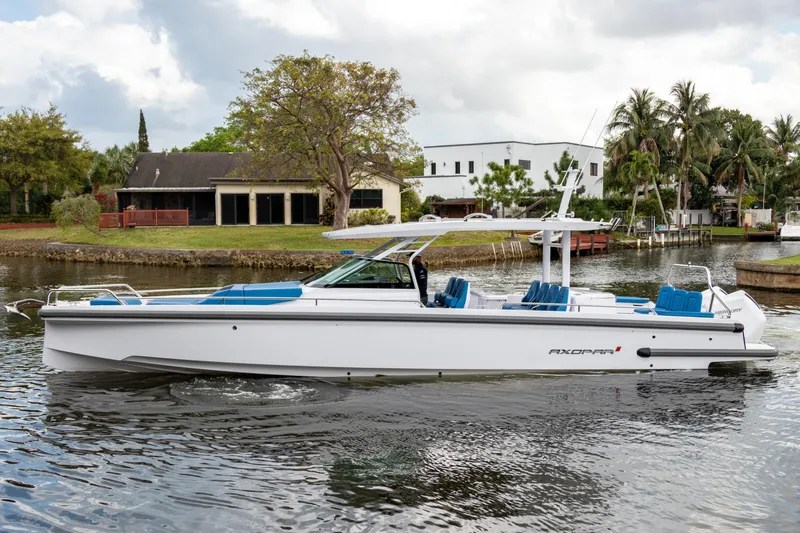 Slide: The Image of 2024 Axopar 37 Sun Top boat on a calm waterway, surrounded by lush greenery. - 22
