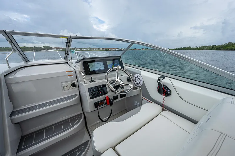 Slide: The Image of 2022 Regal 26 XO boat interior with steering wheel and dashboard, overlooking calm waters. - 16