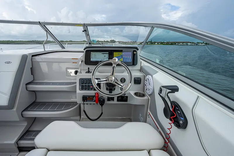 Slide: The Image of 2022 Regal 26 XO boat cockpit with modern controls and steering wheel on a calm lake. - 17