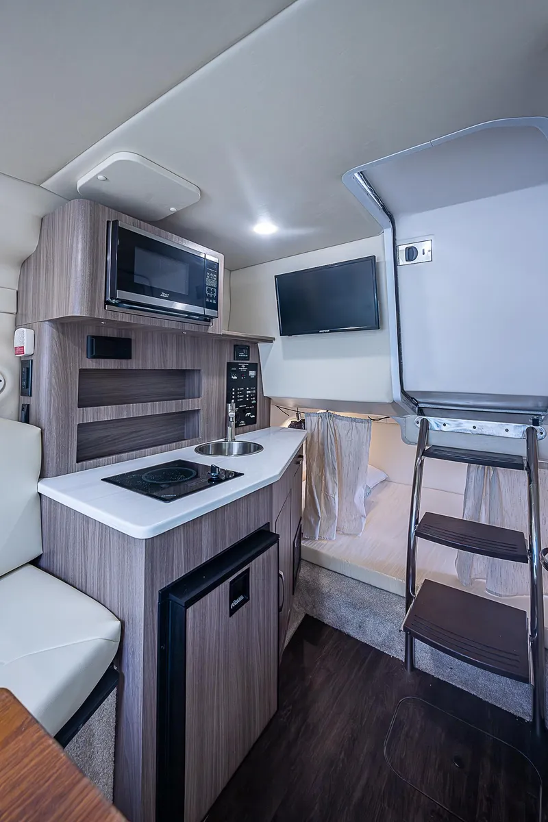 Slide: The Image of 2022 Regal 26 XO boat interior with kitchenette, microwave, and TV. - 3