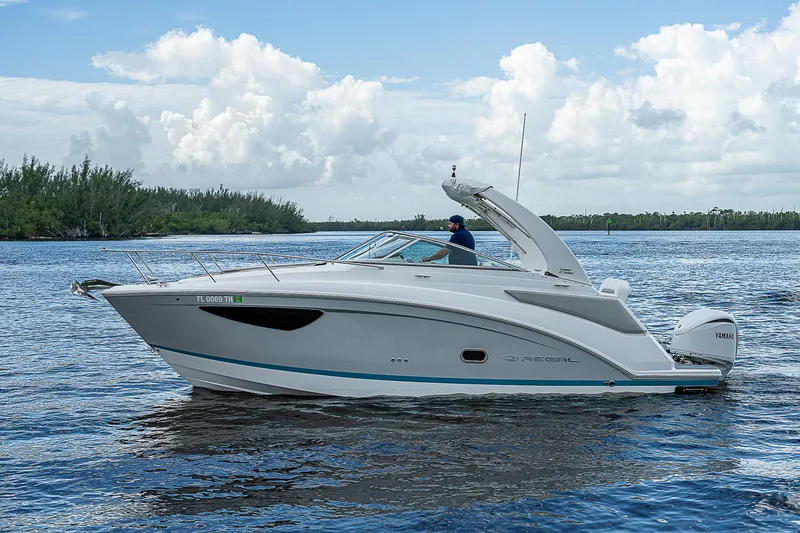 Slide: The Image of 2022 Regal 26 XO boat cruising on a serene lake under a cloudy sky. - 32