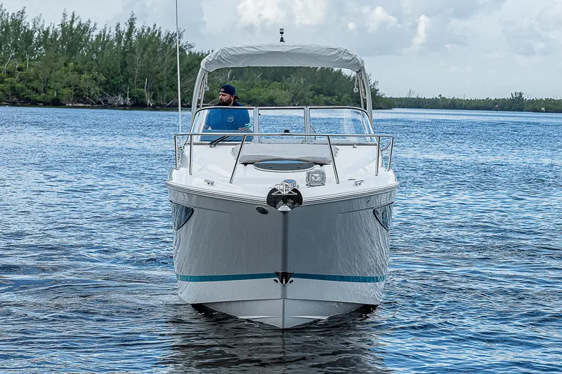 Slide: The Image of 2022 Regal 26 XO boat cruising on a serene lake with lush greenery. - 35