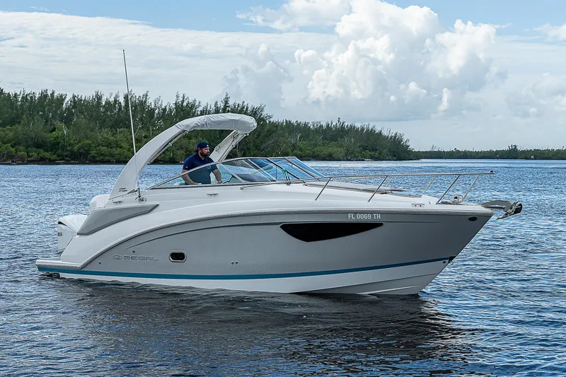 Slide: The Image of 2022 Regal 26 XO boat cruising on a serene lake under a cloudy sky. - 37