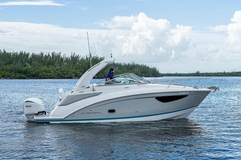Slide: The Image of 2022 Regal 26 XO boat cruising on a serene lake under a clear sky. - 38